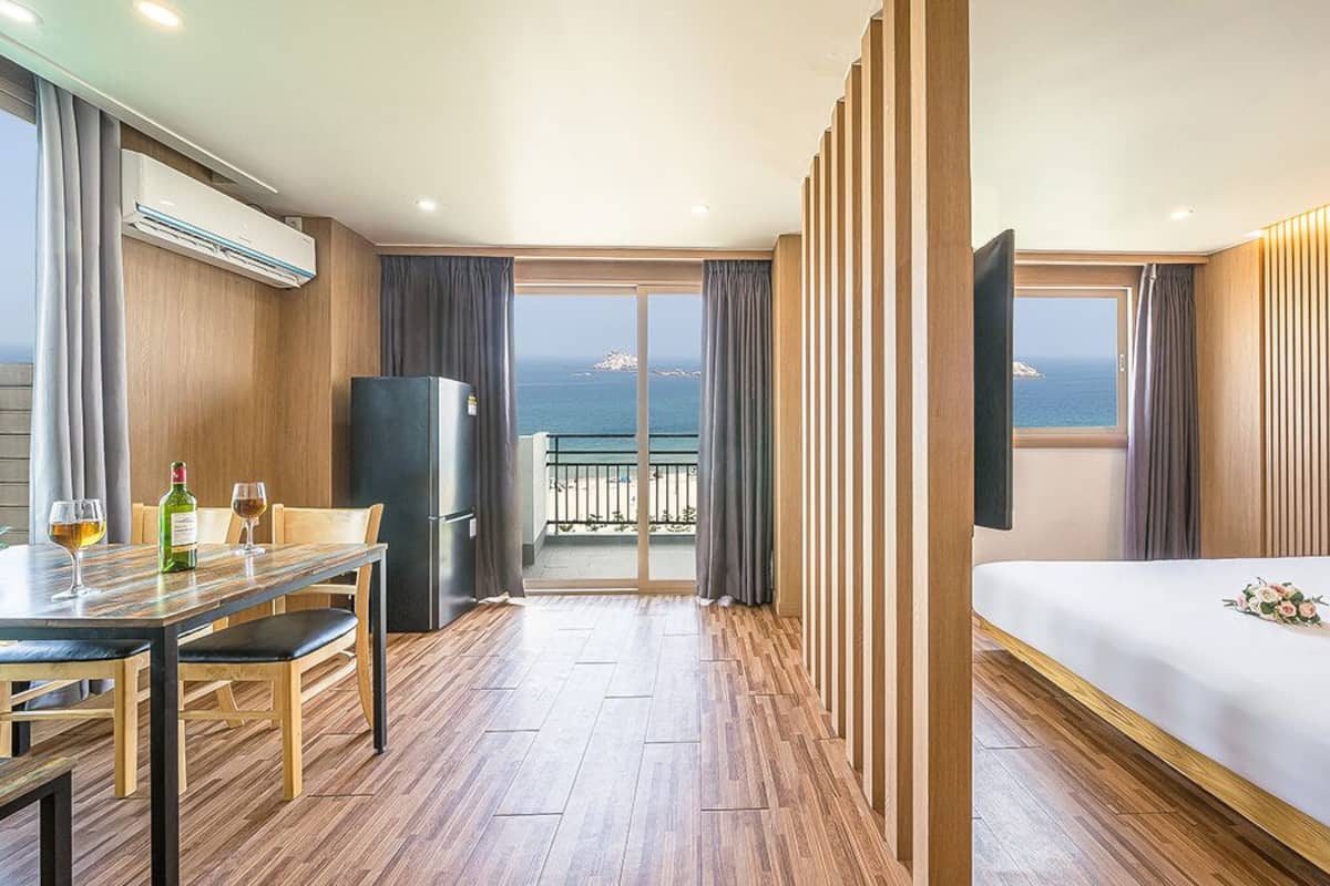 A hotel room with a balcony, a dining area, and a bed.