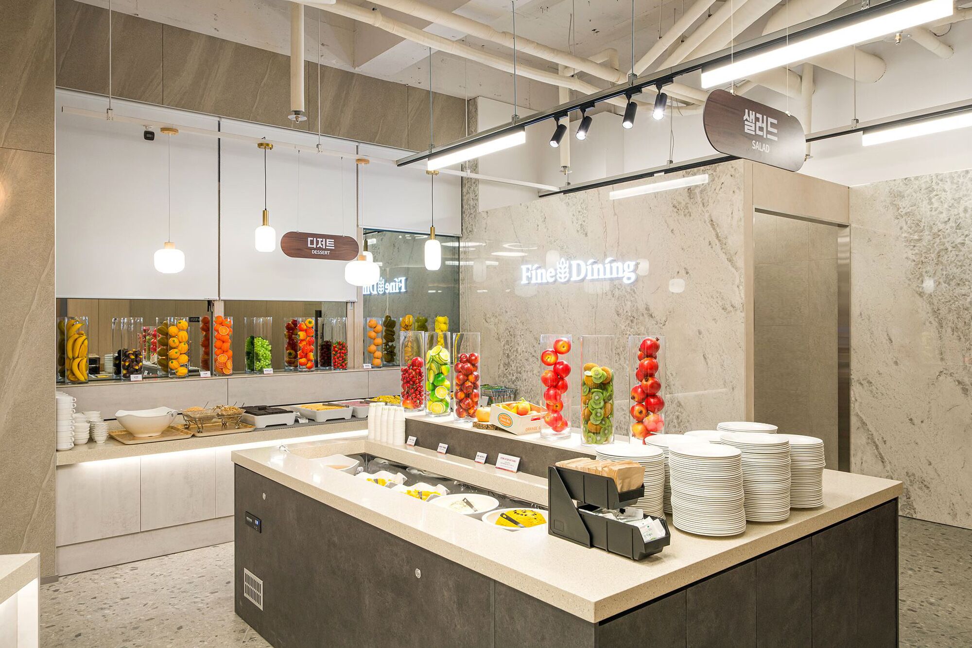 A buffet area with a variety of fruits and vegetables displayed in clear containers, a salad bar, and a dessert section.