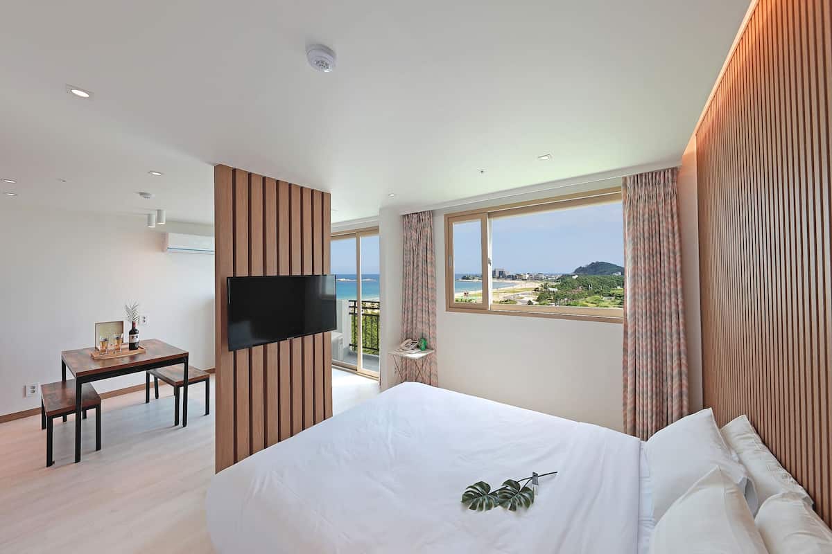 A modern hotel room with a large bed, a desk, and a TV.