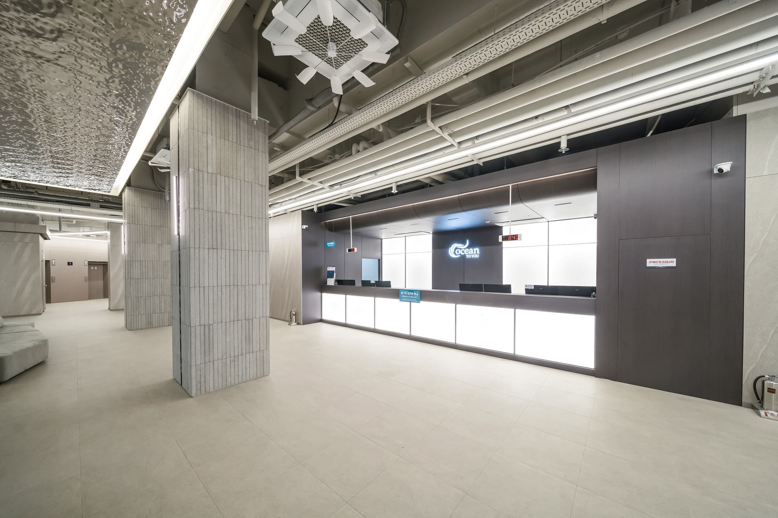 Un'accogliente area reception moderna e ben illuminata, con un display digitale e una insegna con il nome 'Ocean'.