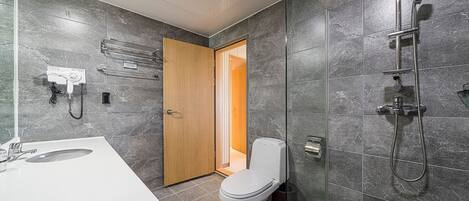 Een moderne badkamer met douche, toilet en wastafel.