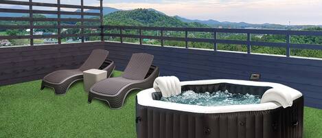 Una terraza en la azotea con dos sillones de relax, una mesita y un jacuzzi.