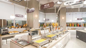 Un espace buffet proposant différents stands de restauration, notamment un coin dédié à la cuisine coréenne, une boulangerie et un espace réservé aux desserts.