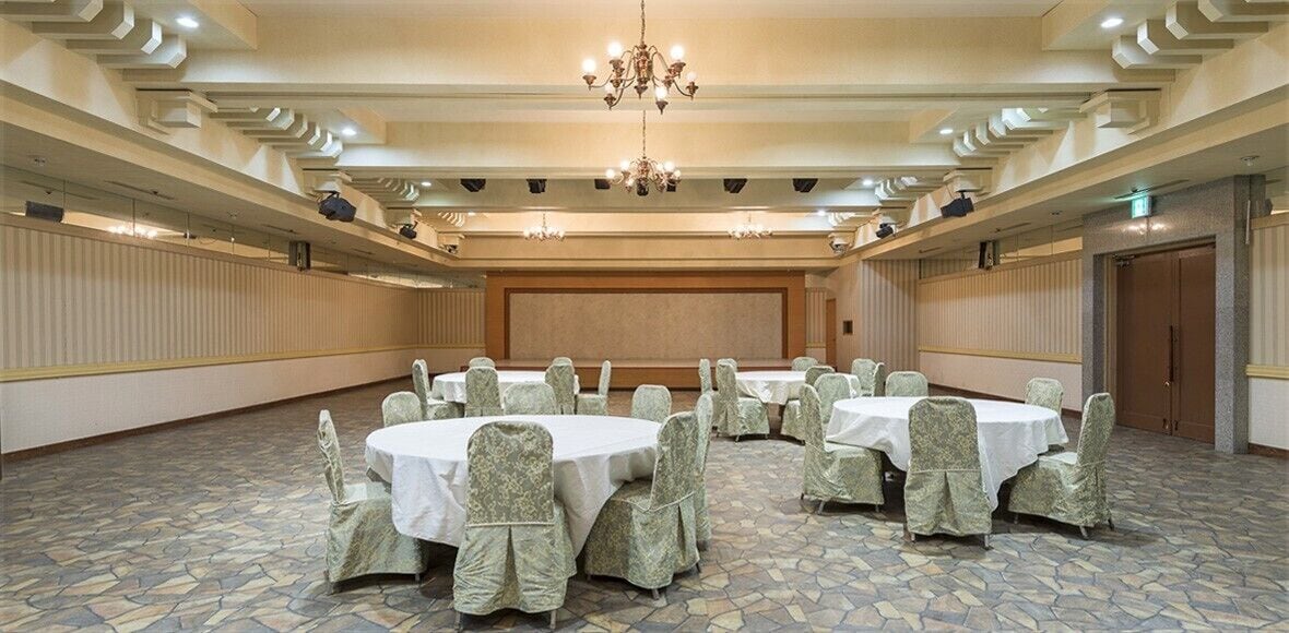 A conference room with round tables, chairs, and a large screen.
