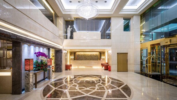 A spacious lobby with a marble floor, a reception desk, a chandelier, and a glass elevator. - Grand View Hotel (Yuanlin)