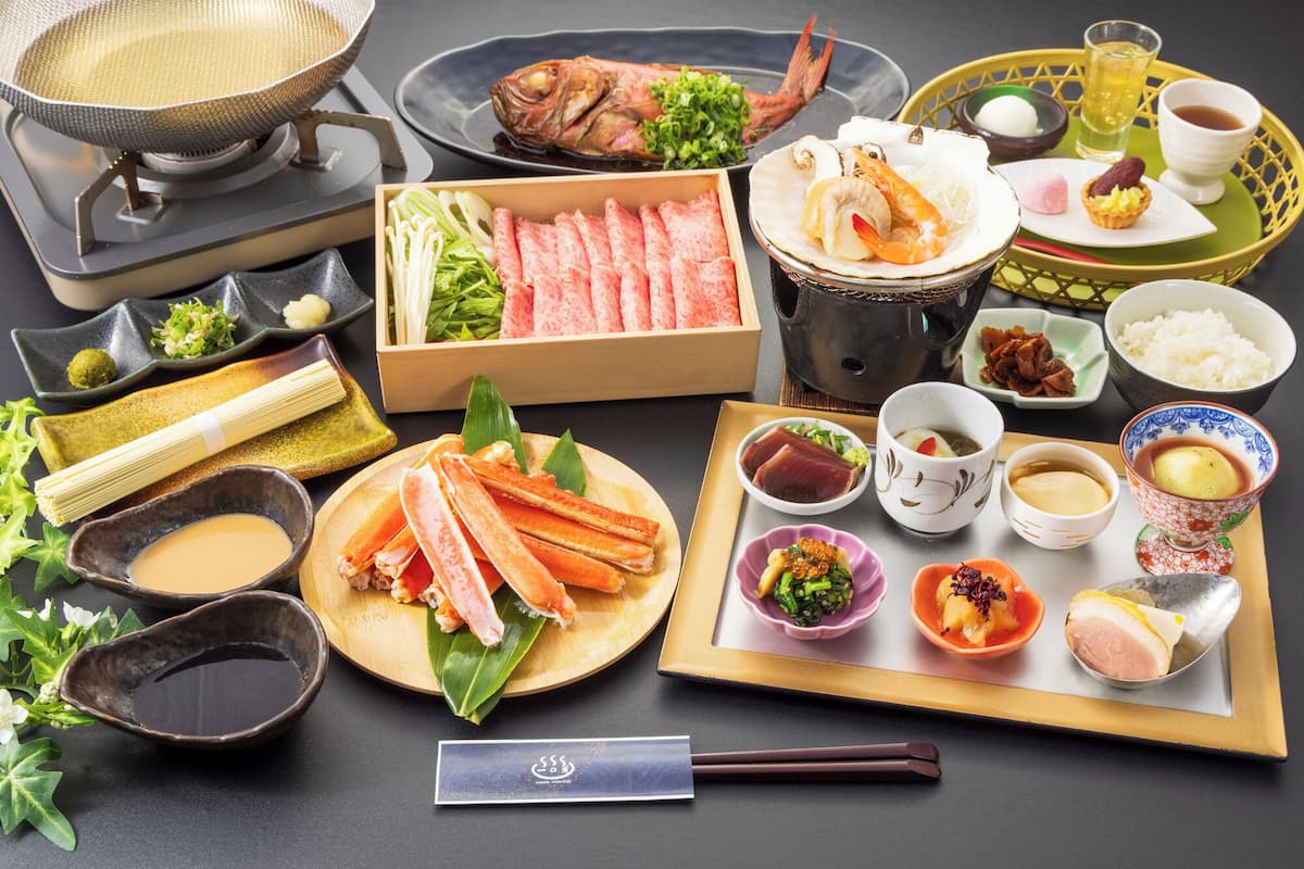 Verschiedene japanische Gerichte, darunter Meeresfrüchte, Reis und eingelegtes Gemüse, an einem Tisch mit Essstäbchen und einem Teekännchen angerichtet.