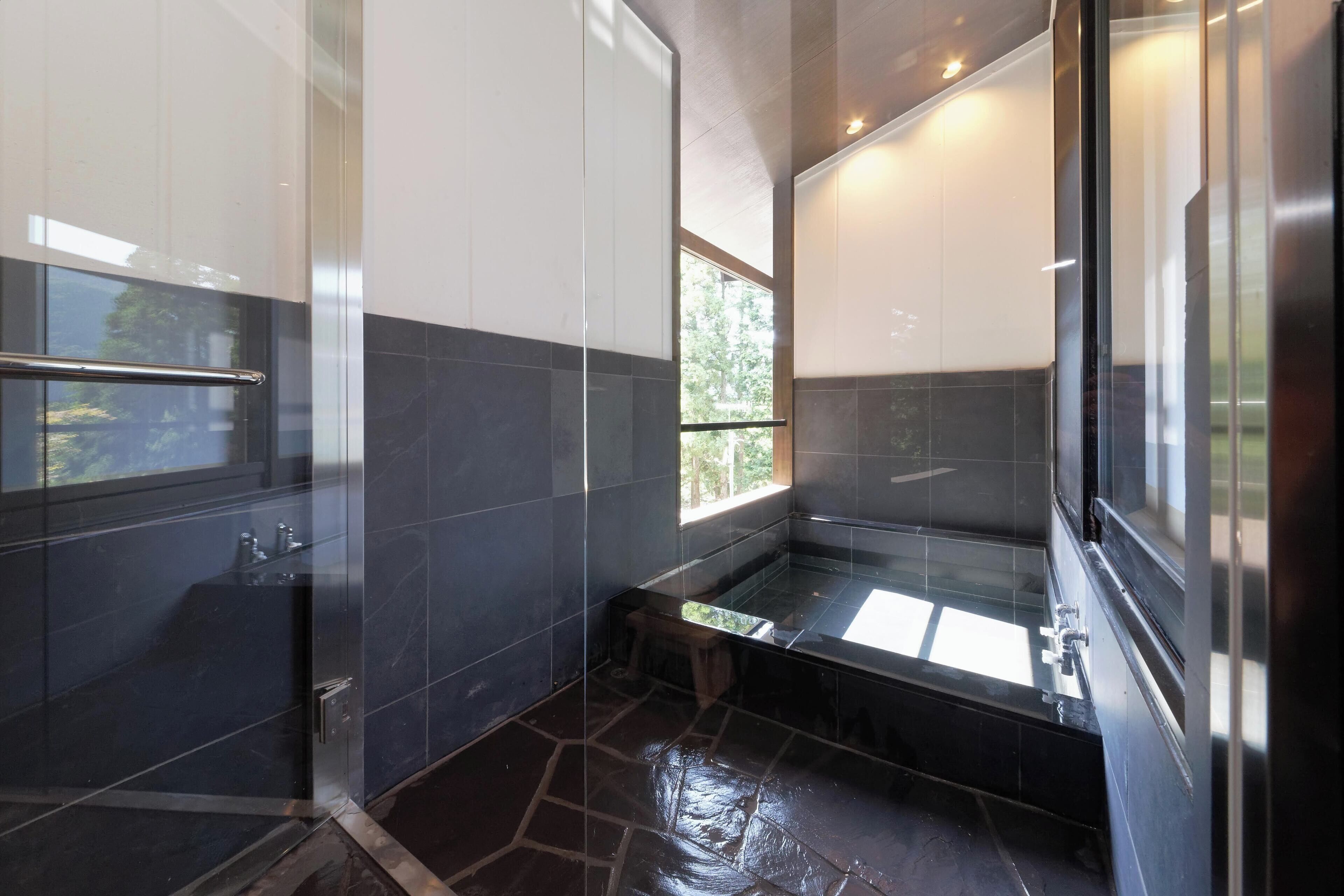 Un baño moderno con cabina de ducha de vidrio, un banco y un taburete pequeño.