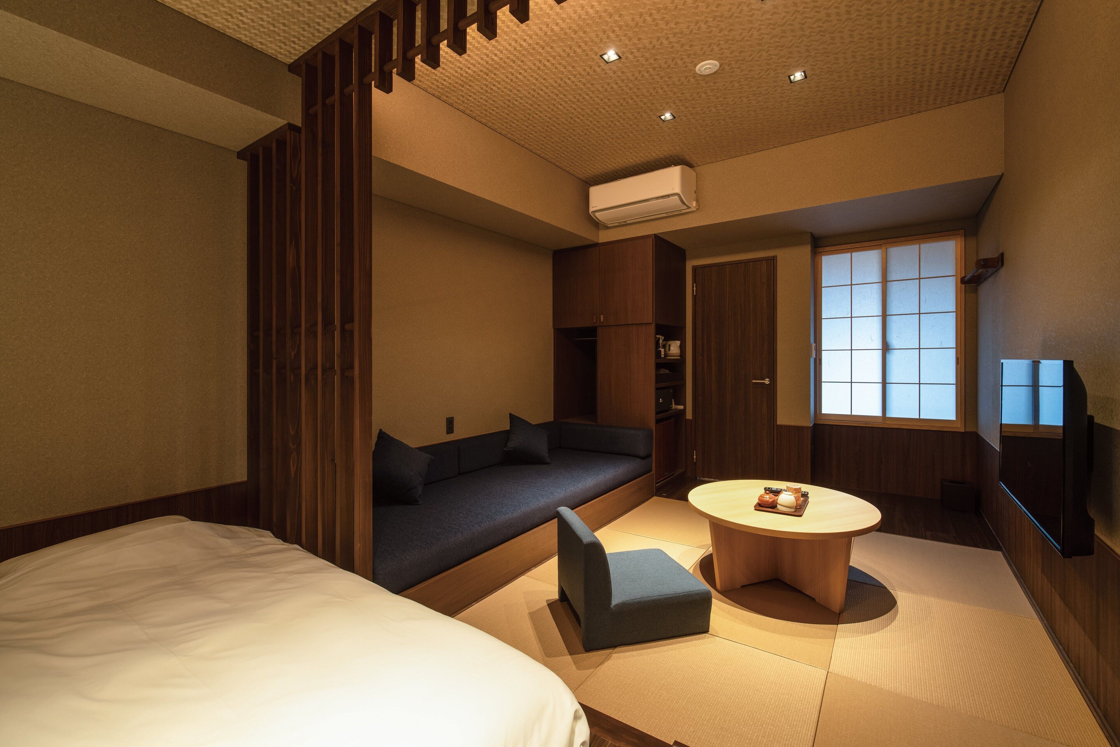 A modern hotel room with a sofa, a small table, and a bed.