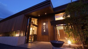 Een modern gebouw met een houten gevel, een grote ingang en een banner met Japanse tekens.