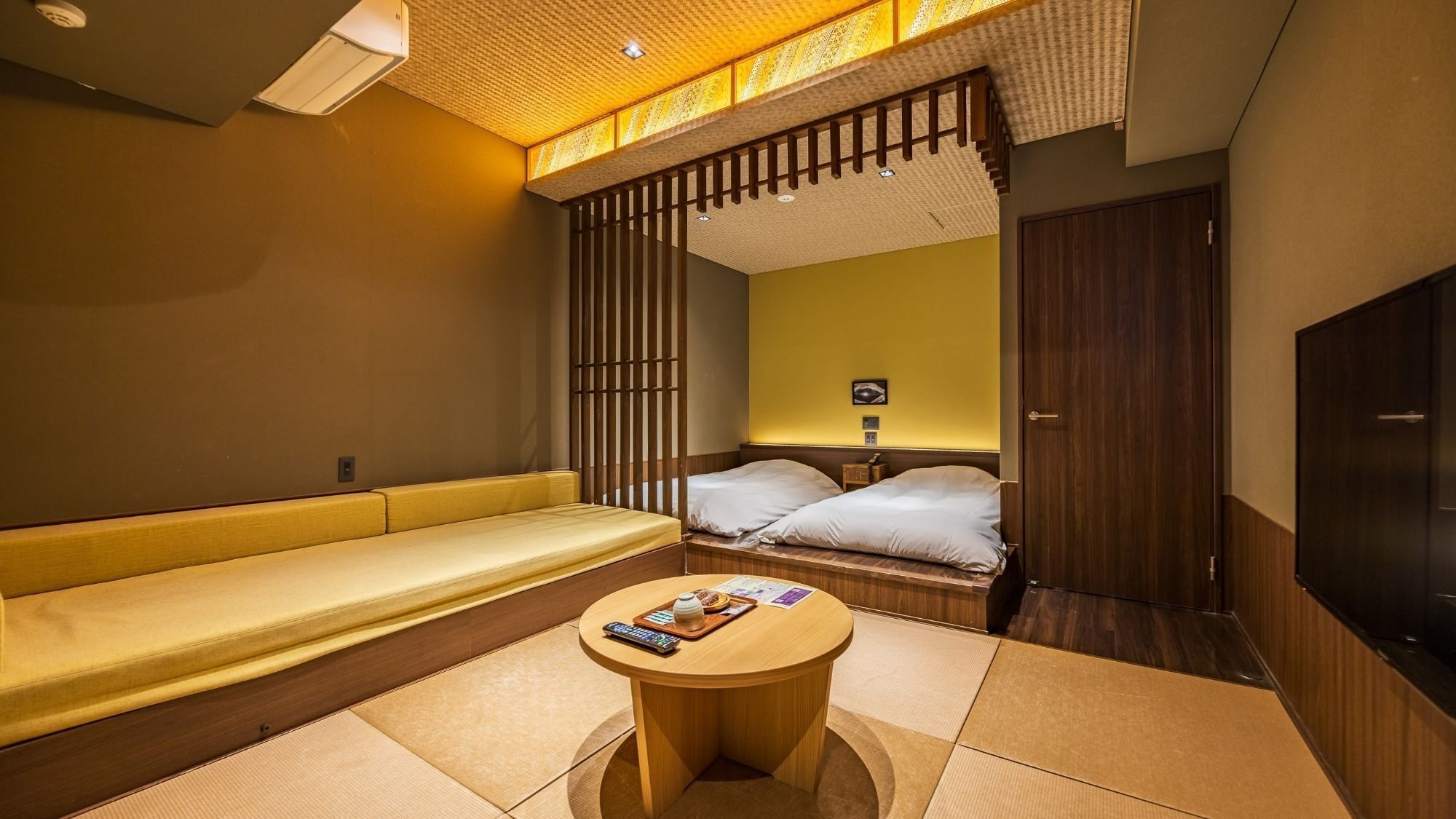 Une chambre d’hôtel avec un canapé, deux lits, une petite table et un téléviseur.