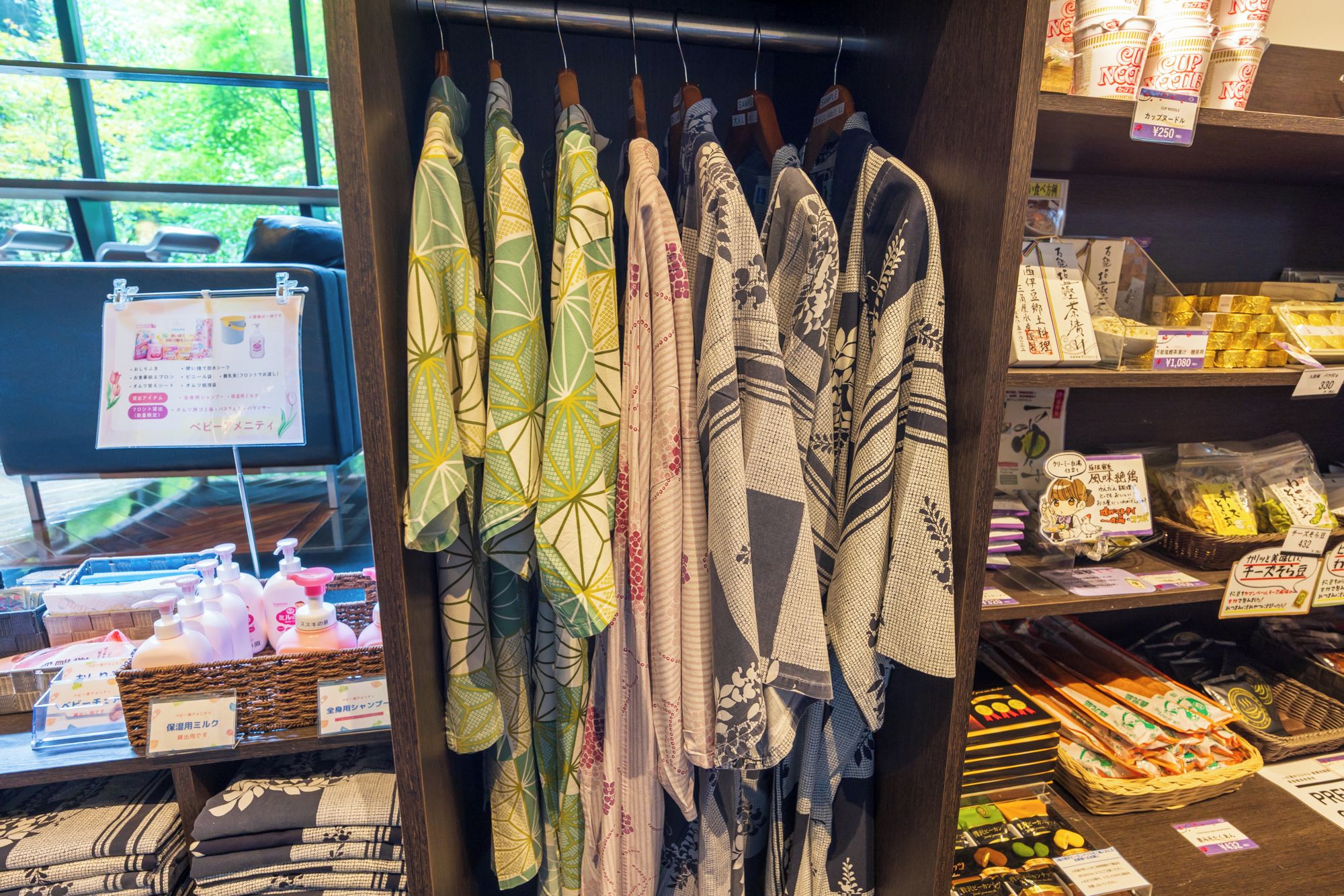 Una exhibición de telas estampadas colgadas en un perchero, con varios artículos y etiquetas de precios a la vista en el fondo.