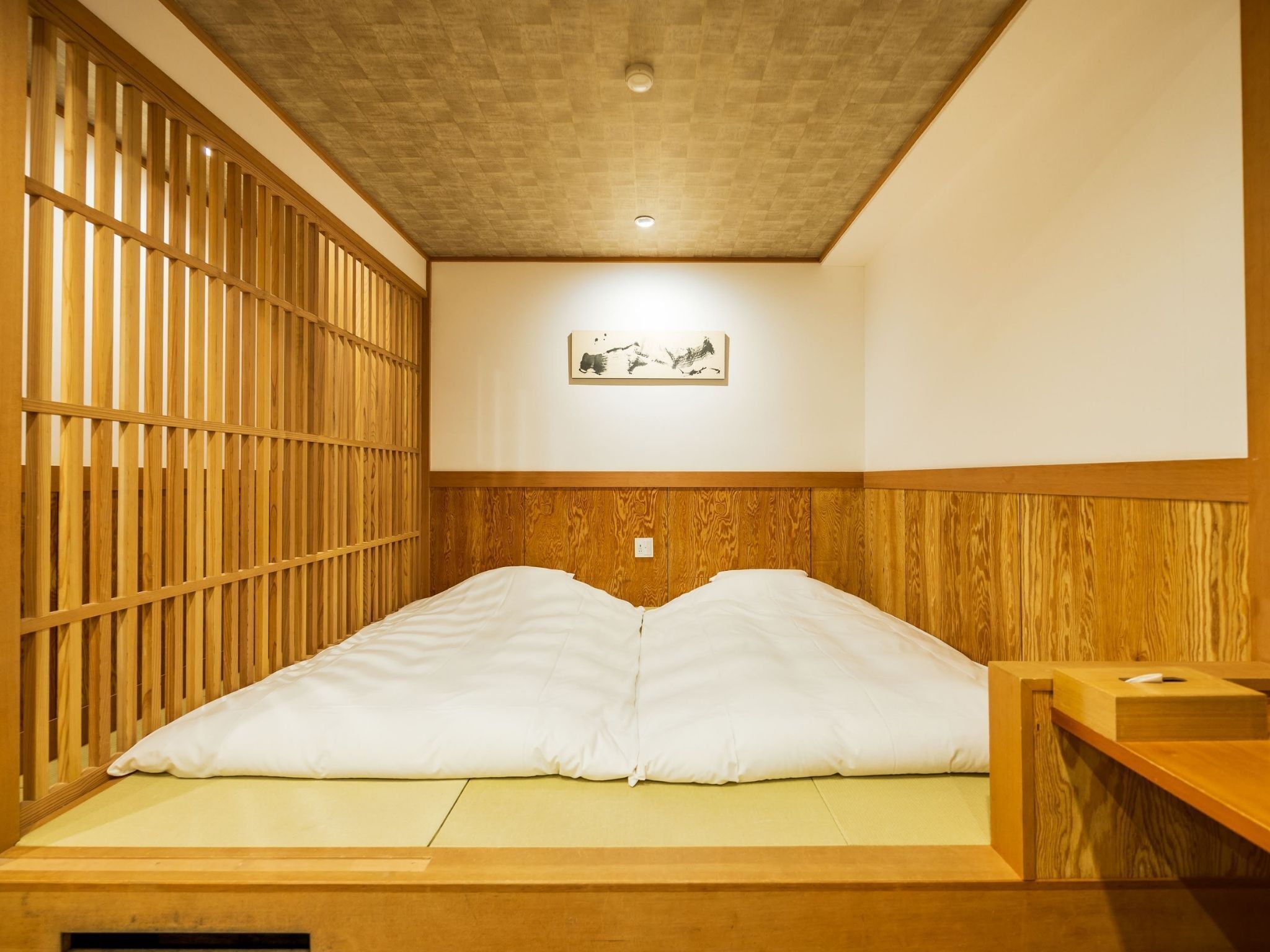 A room with a wooden bed frame, a wooden headboard, and a wall-mounted picture.