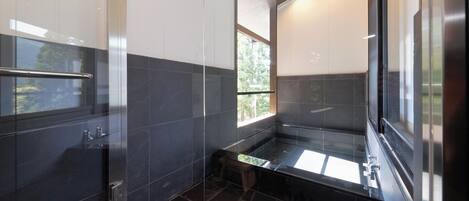 A modern bathroom with a glass shower enclosure, a bench, and a small stool.