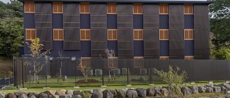 A modern building with a dark facade, vertical wooden slats, and multiple windows.