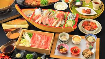 A variety of Japanese dishes, including sashimi, sushi, and tempura, arranged on a table with chopsticks and small bowls of condiments.