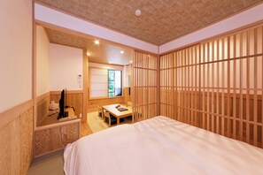 Une pièce de style japonais traditionnel, comprenant un lit, un bureau en bois et une porte coulissante.