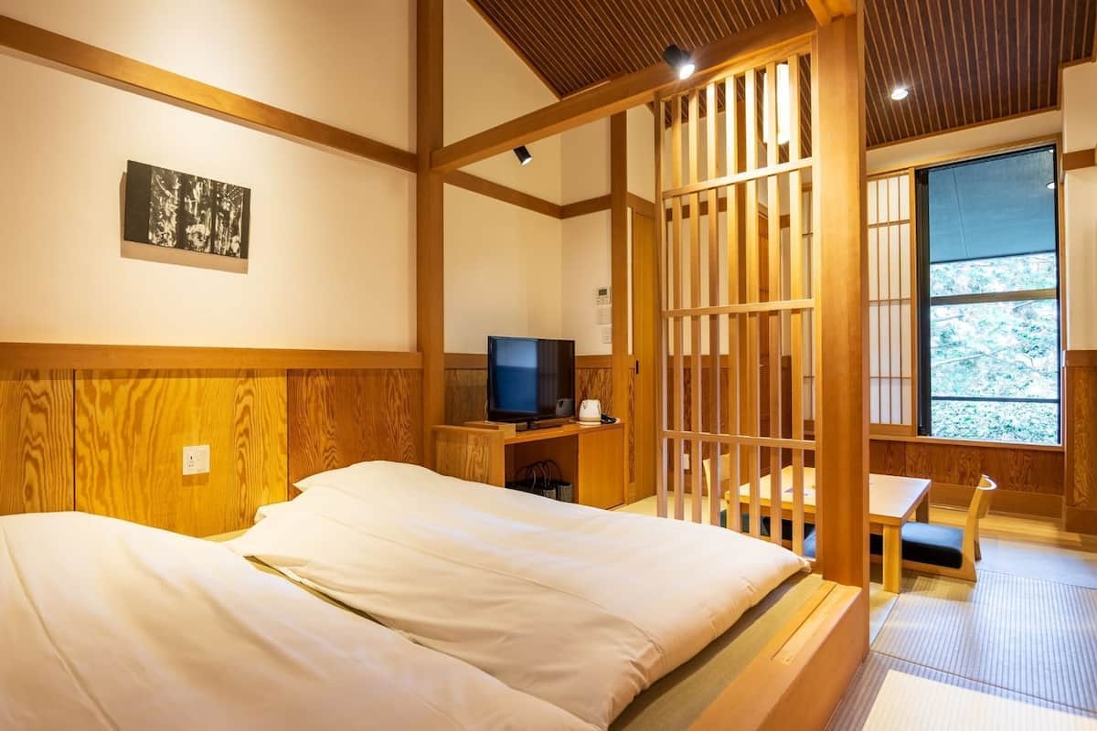 Ein Zimmer mit einem Bett, einem Fernseher und Blick durch eine Holzabtrennung.