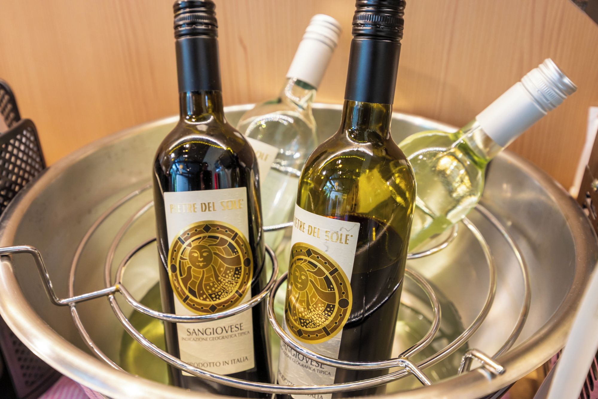 Two bottles of wine with labels, placed in a metal container.