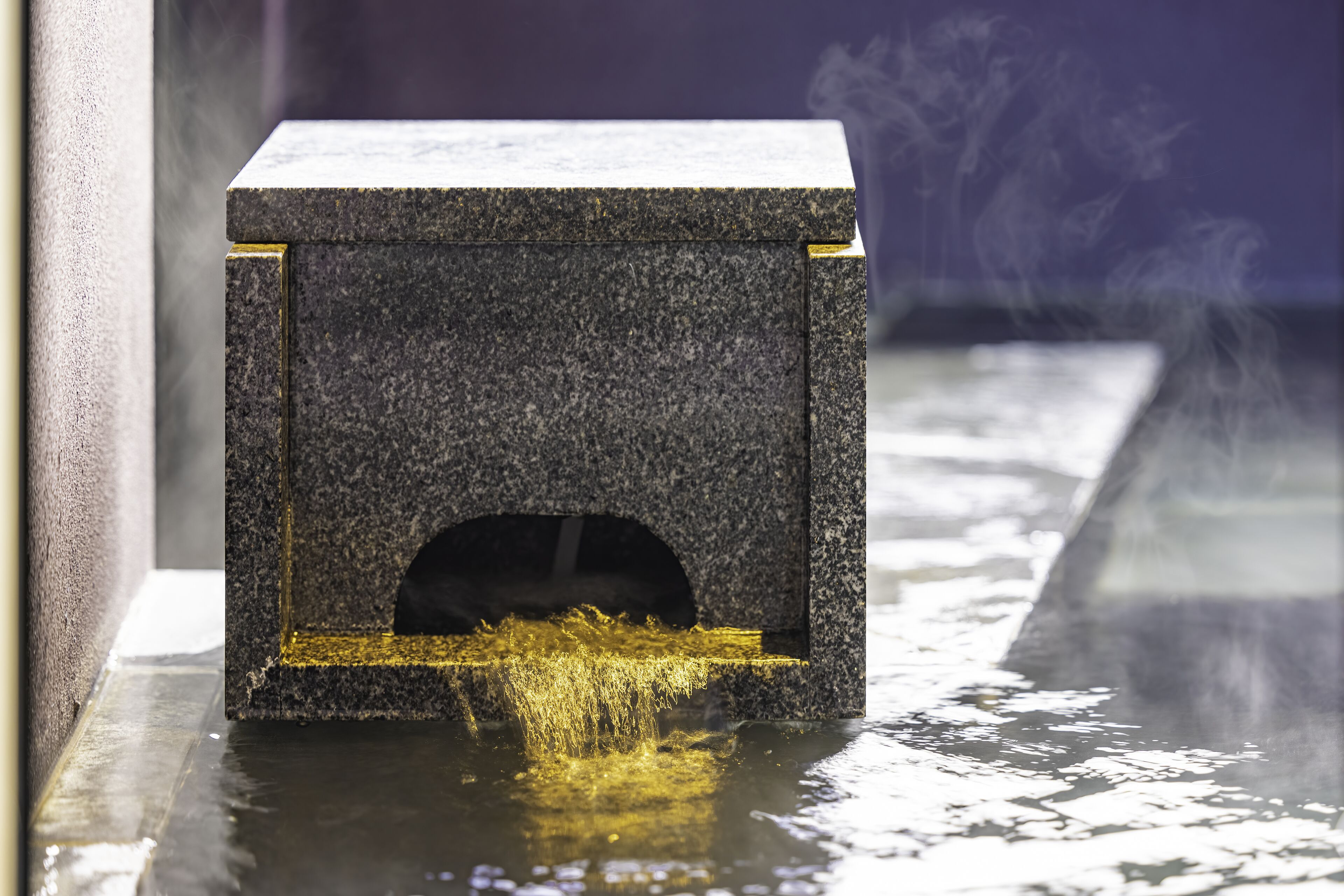 A small, dark-colored, rectangular object with a hole at the bottom, emitting a yellowish liquid.