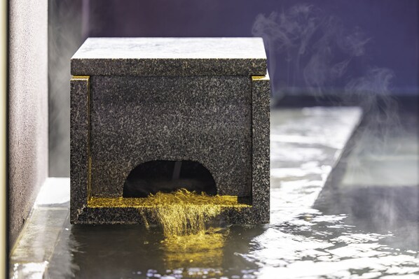 A small, dark-colored, rectangular object with a hole at the bottom, emitting a yellowish liquid.