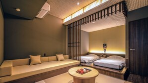 Una habitación de hotel moderna con sofá, cama, una mesa redonda y un separador.
