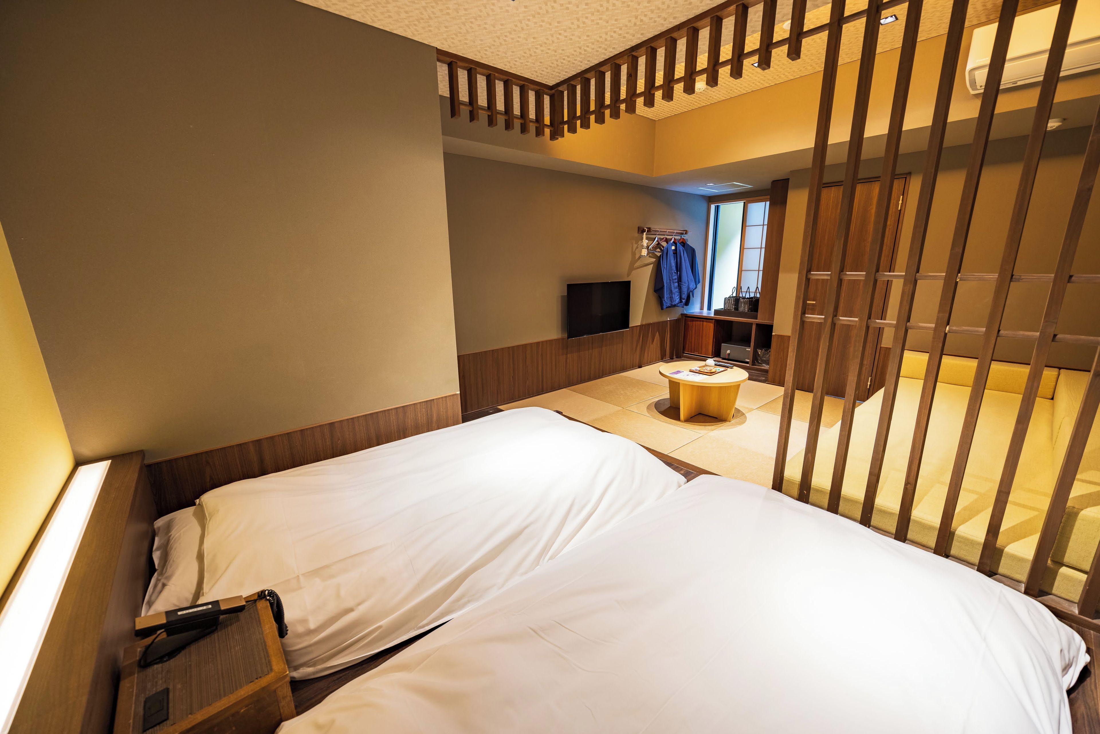 Une chambre d’hôtel avec un lit, une petite table ronde et un téléviseur fixé au mur.