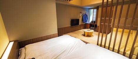 Habitación de hotel con una cama, una mesita redonda y un televisor montado en la pared.