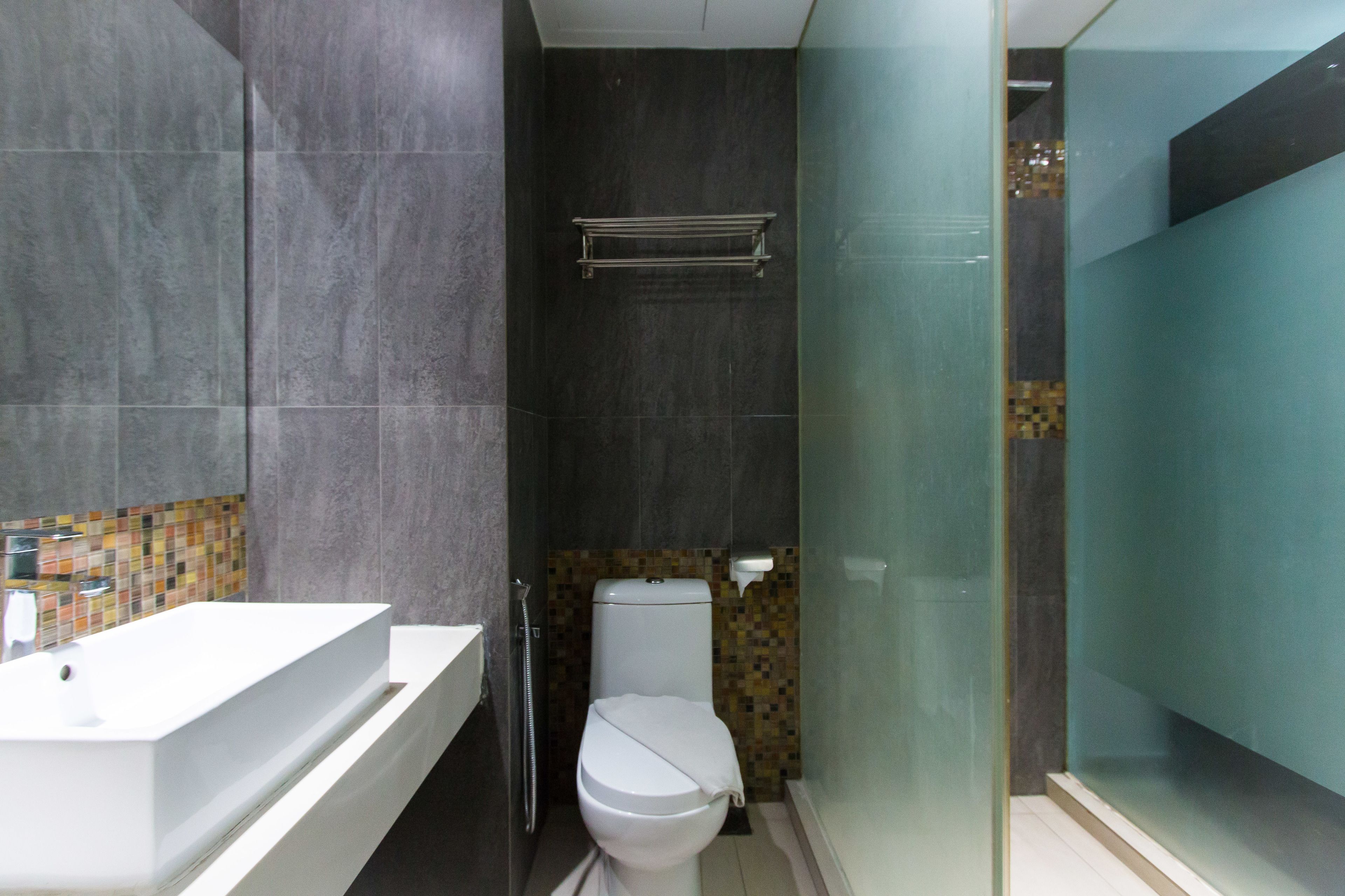 Une salle de bain moderne avec un lavabo blanc, des toilettes et une douche à parois de verre.