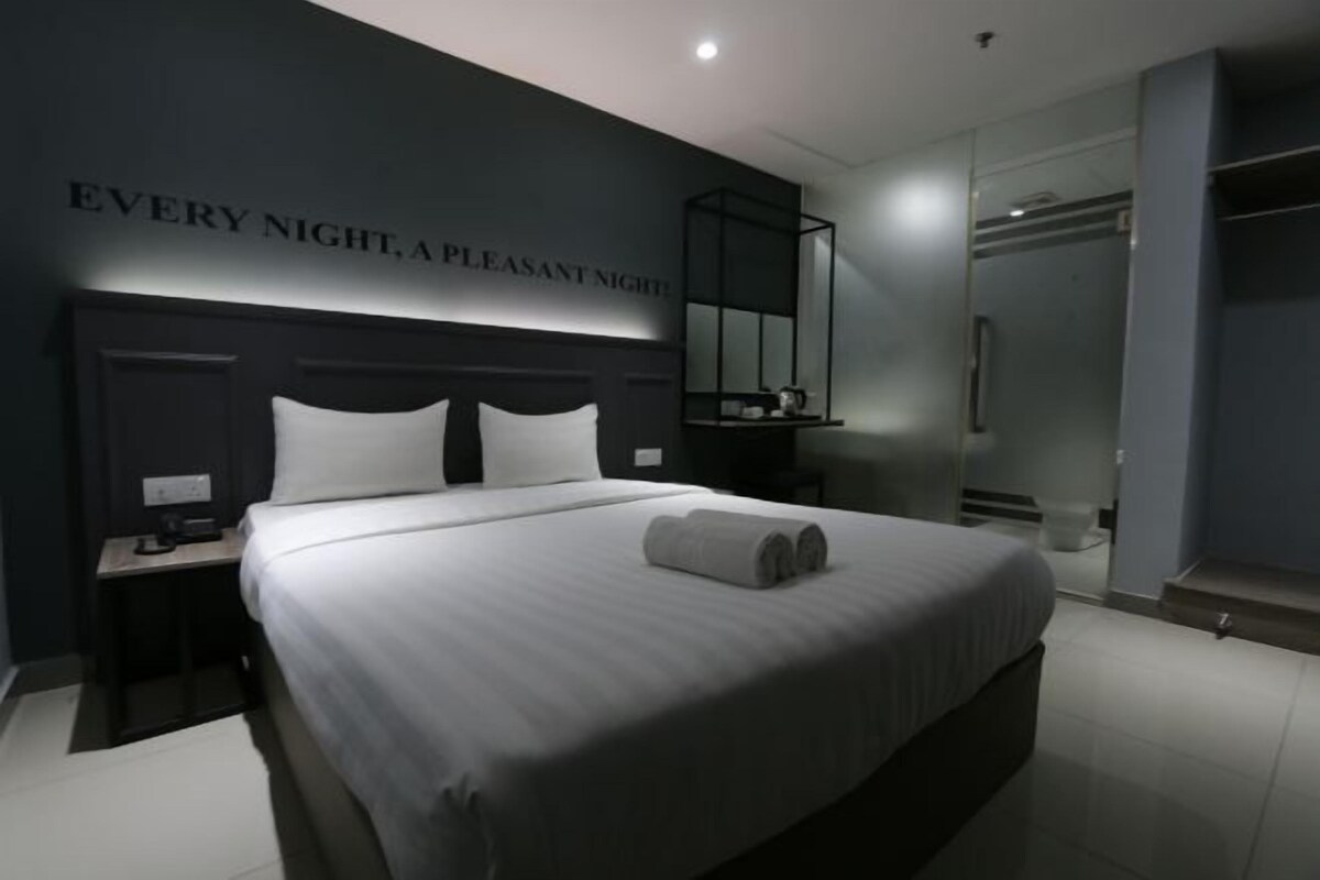 Une chambre d’hôtel moderne avec un grand lit, une table de chevet, un miroir et une armoire.
