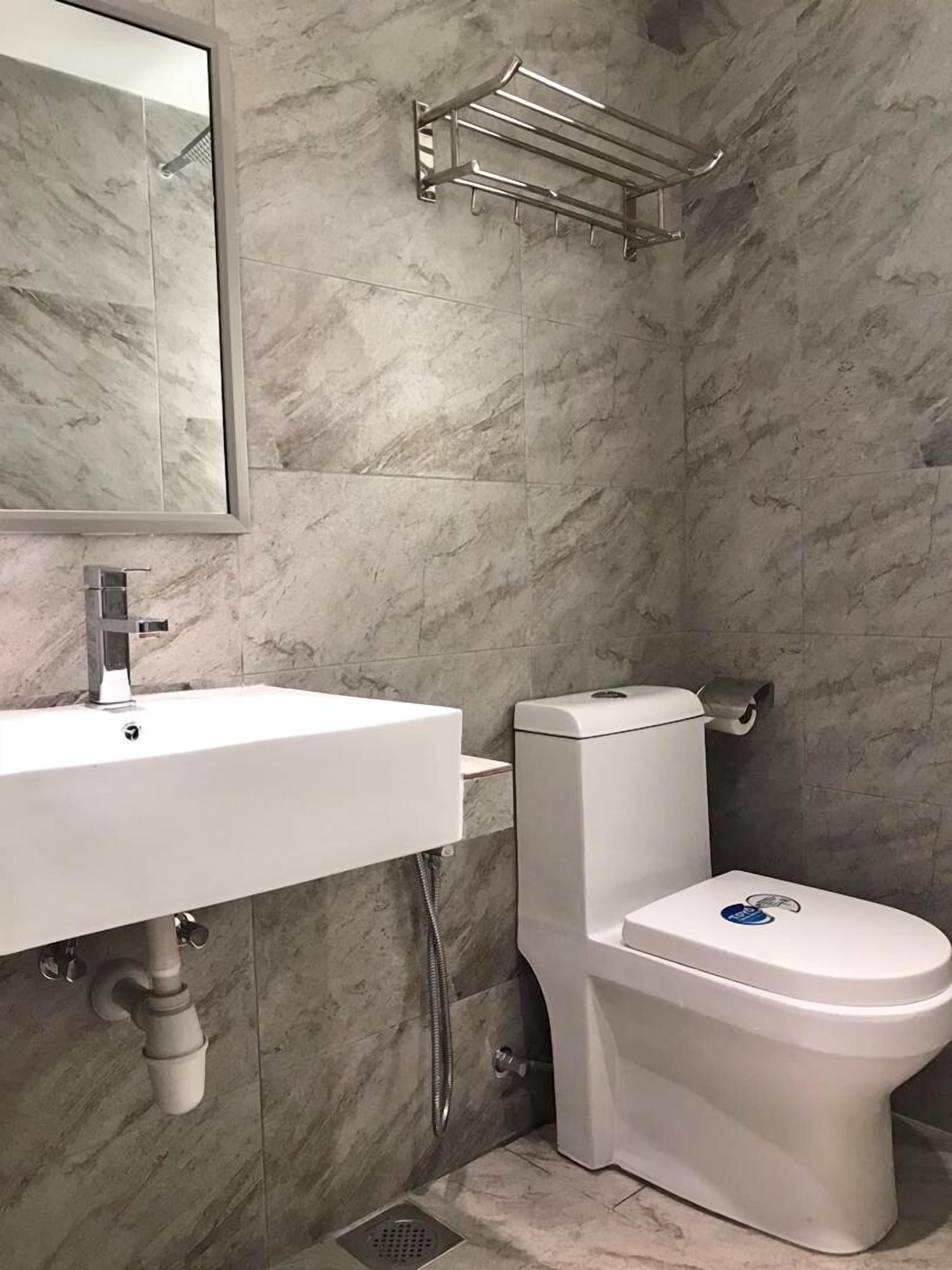 A bathroom with a white sink, a toilet, and a showerhead.