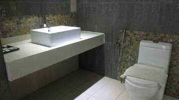 Un bagno moderno con lavandino bianco, un water e zona doccia.