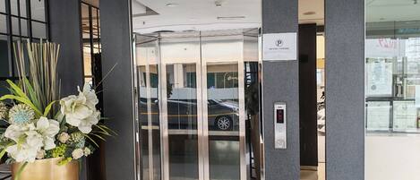 An elevator with glass doors, a 'NO FREE PARKING' sign, and a digital display.