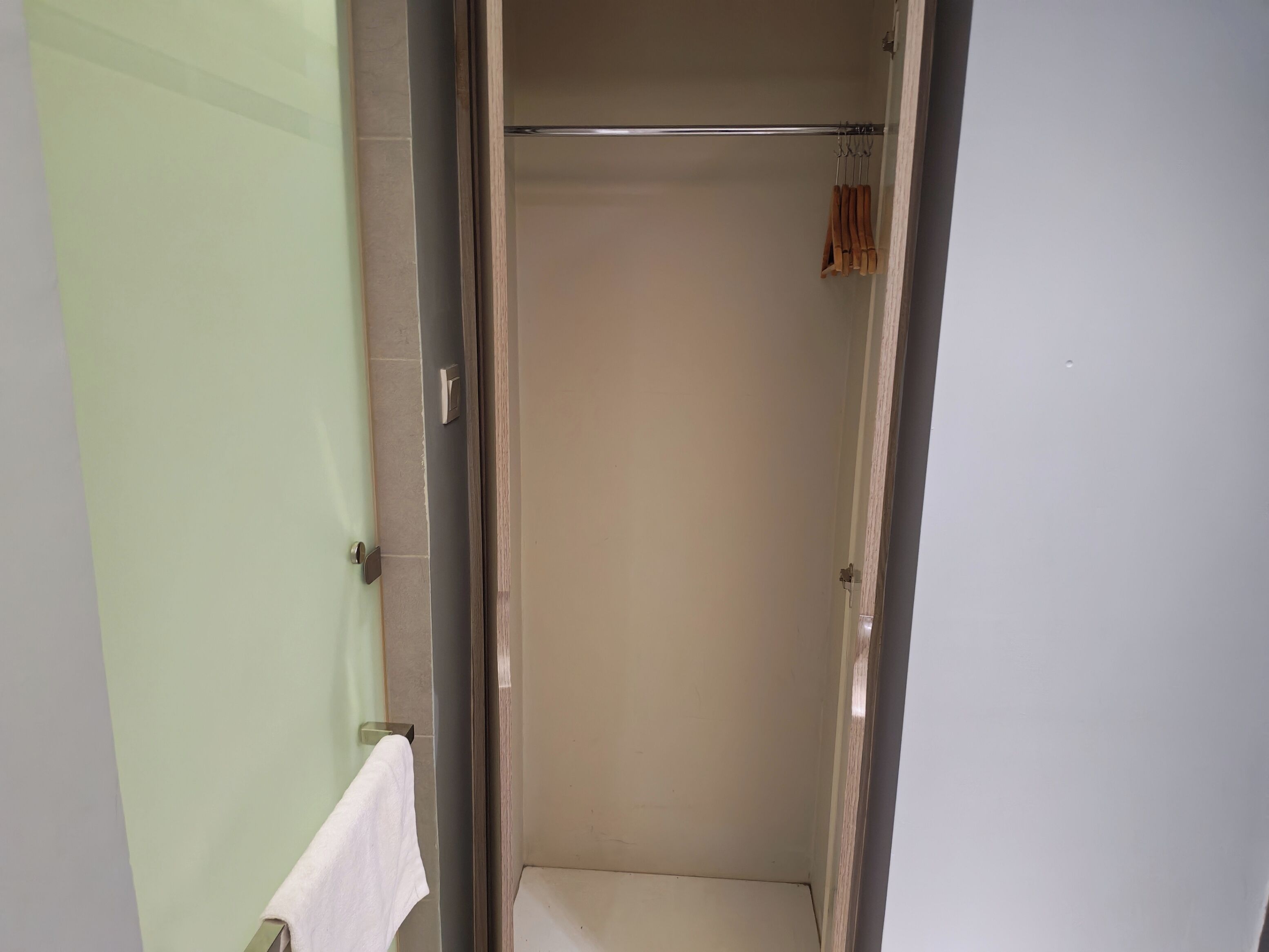 A bathroom with a glass door, a towel rack with a white towel, and a shower area.