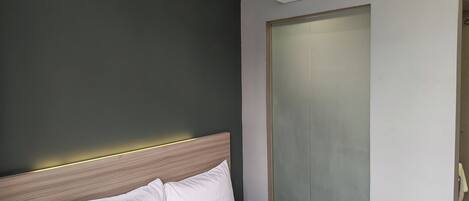 A hotel room with a bed, a wall-mounted air conditioner, and a sliding door closet.