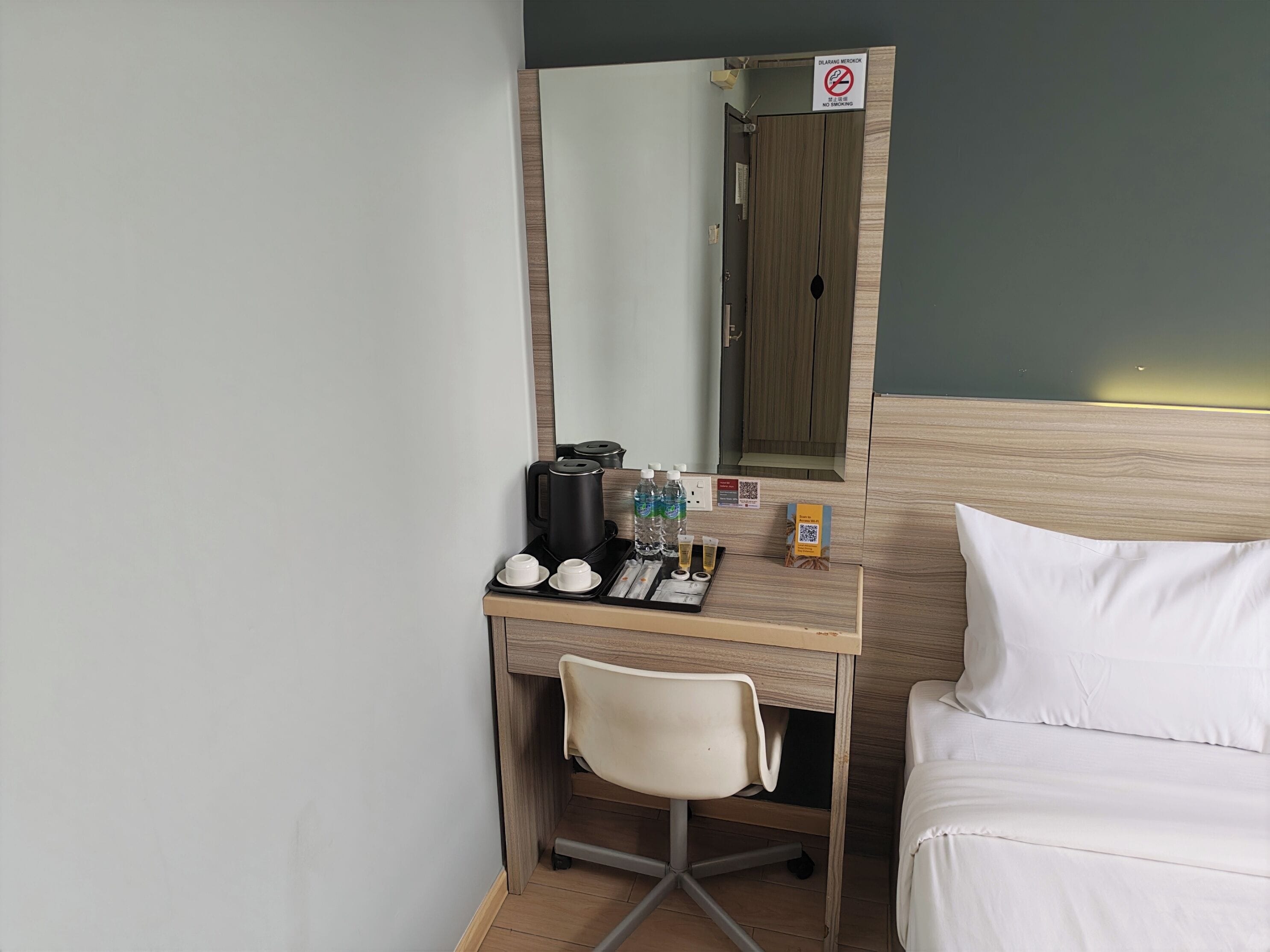 A hotel room with a desk, chair, and a bed.