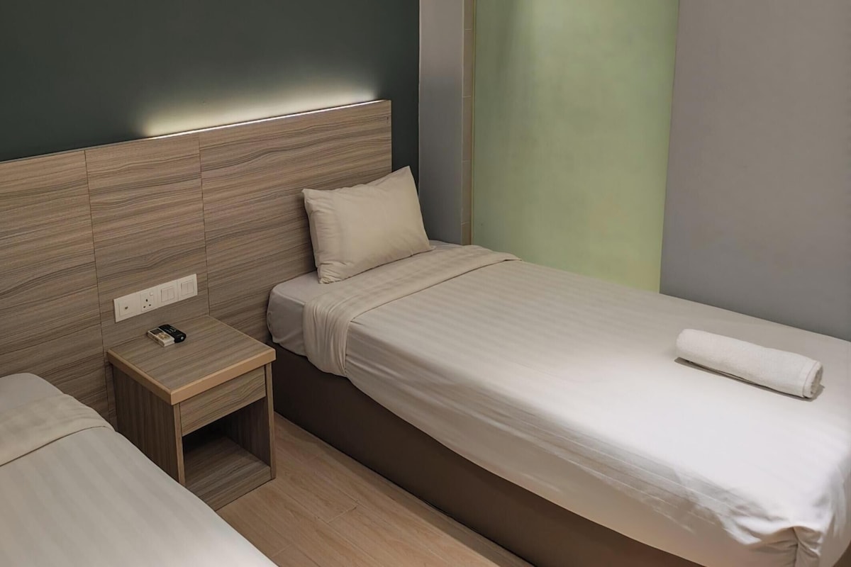 A hotel room with two beds, a nightstand, and a power outlet.