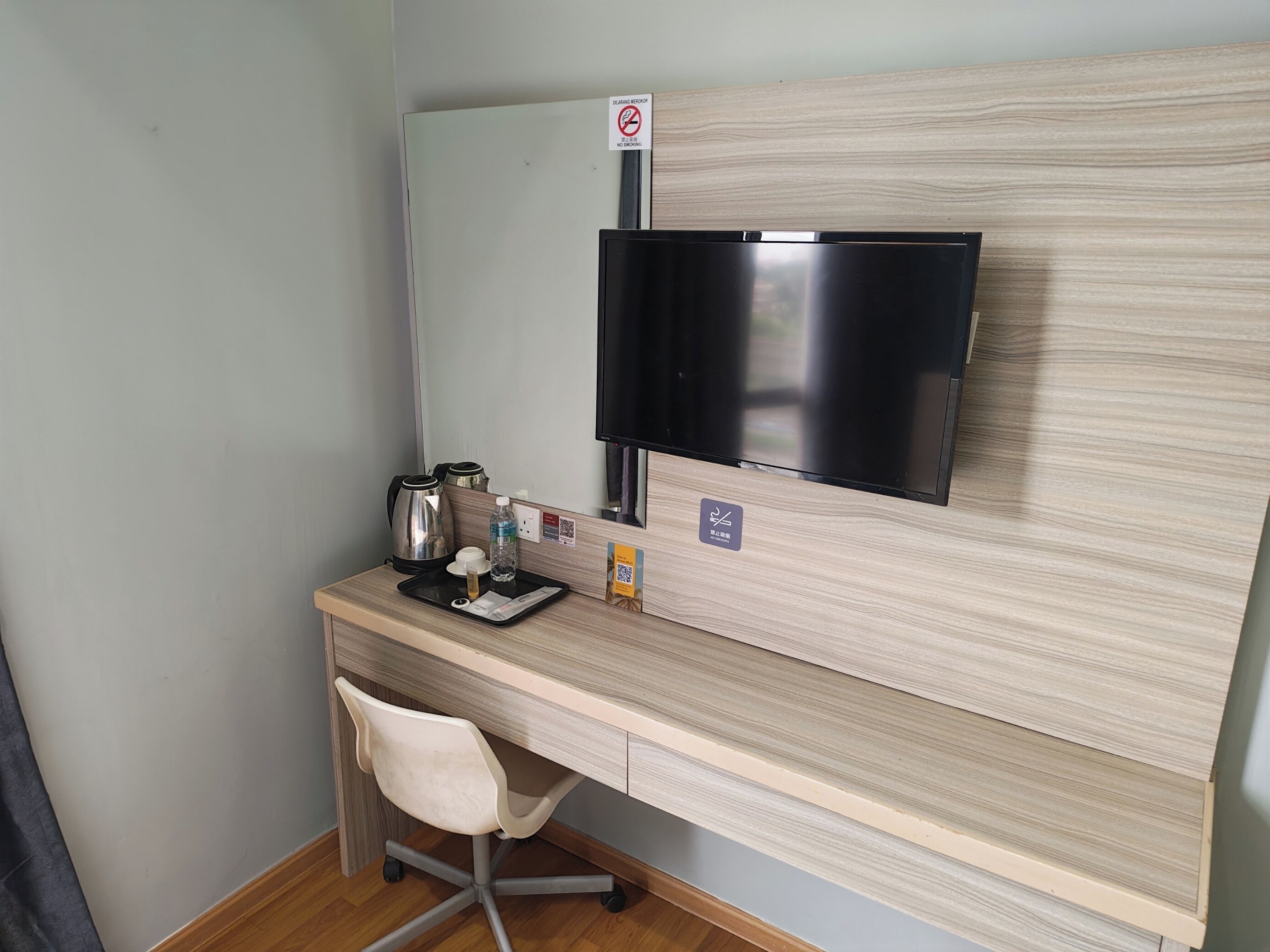 A small, private office with a desk, chair, and a flat-screen TV mounted on a wooden panel.