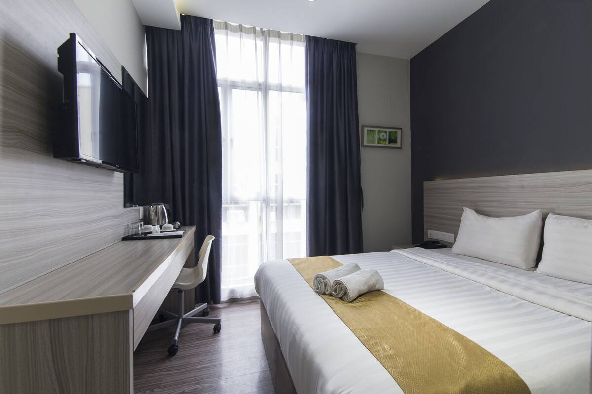 Una habitación de hotel con una cama, un escritorio, una silla y un televisor.