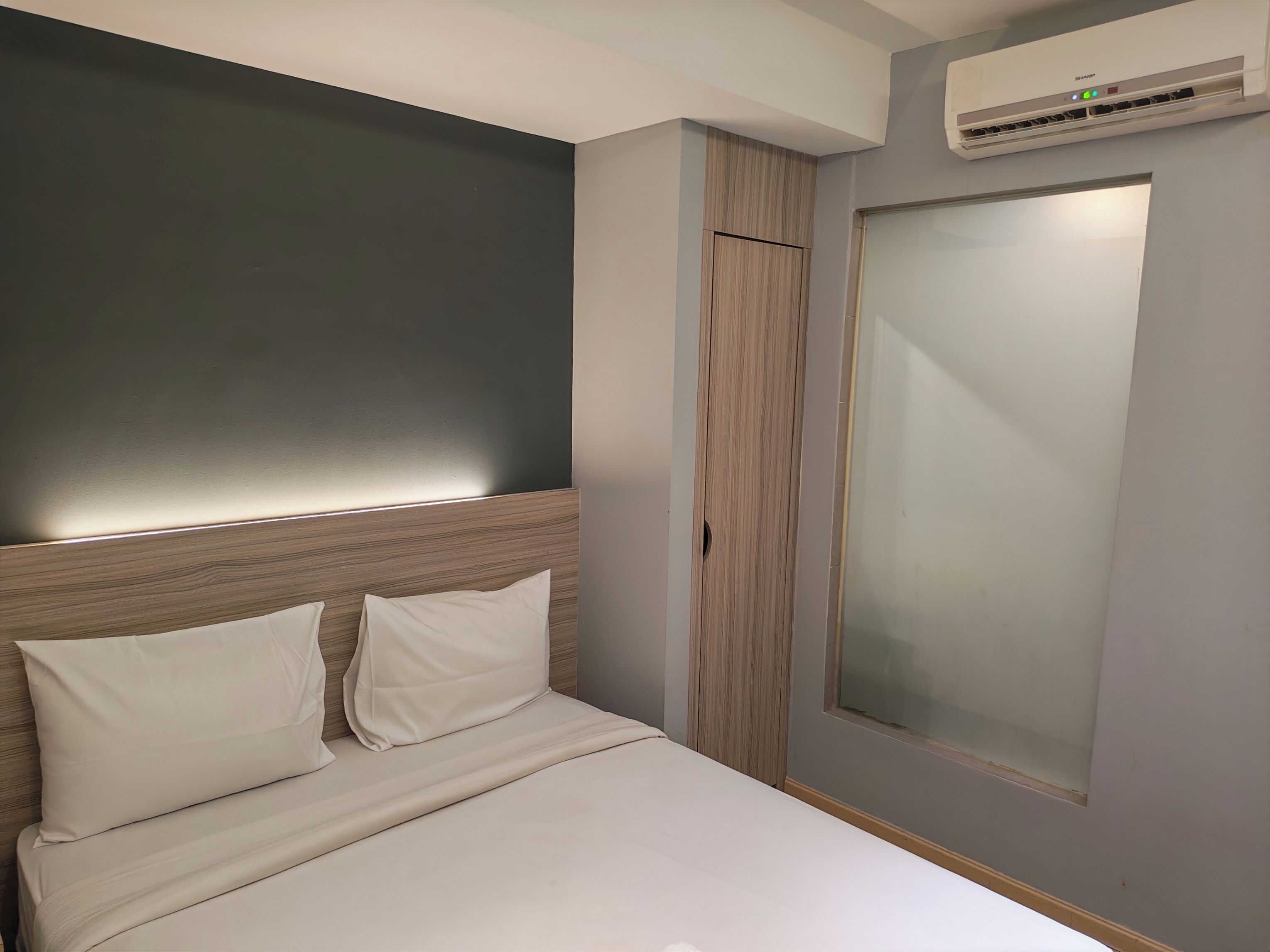 A bedroom with a bed, a wardrobe, and an air conditioning unit.