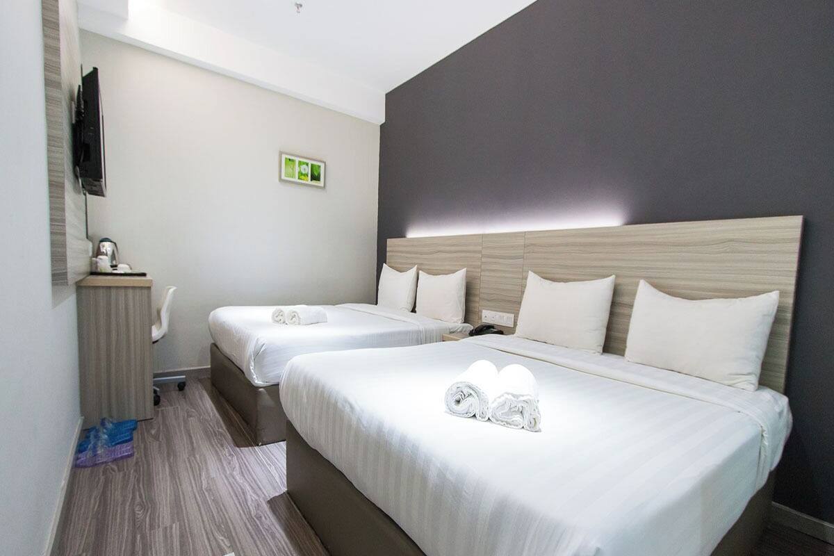 Habitación de hotel con dos camas, un televisor, un escritorio y una silla.