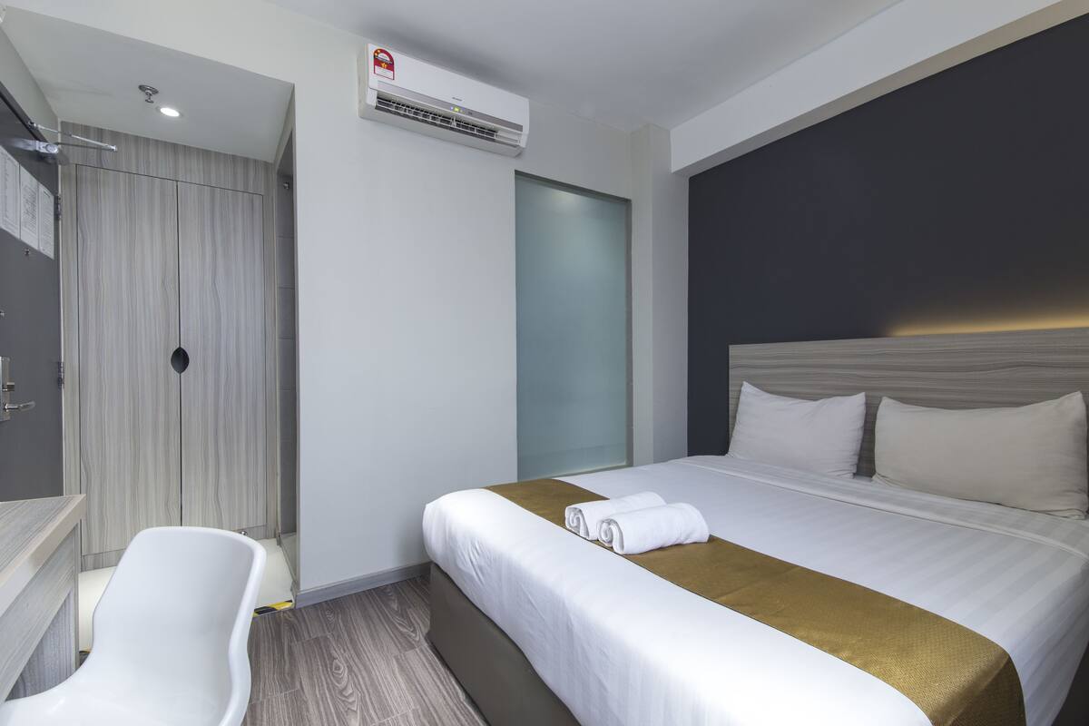 Una habitación de hotel moderna con cama, escritorio y zona de ducha.