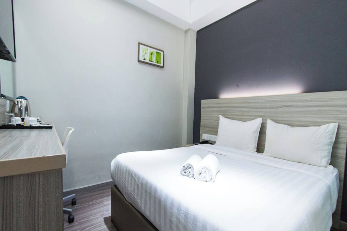 Una habitación de hotel con una cama, un escritorio y un pequeño cuadro en la pared.