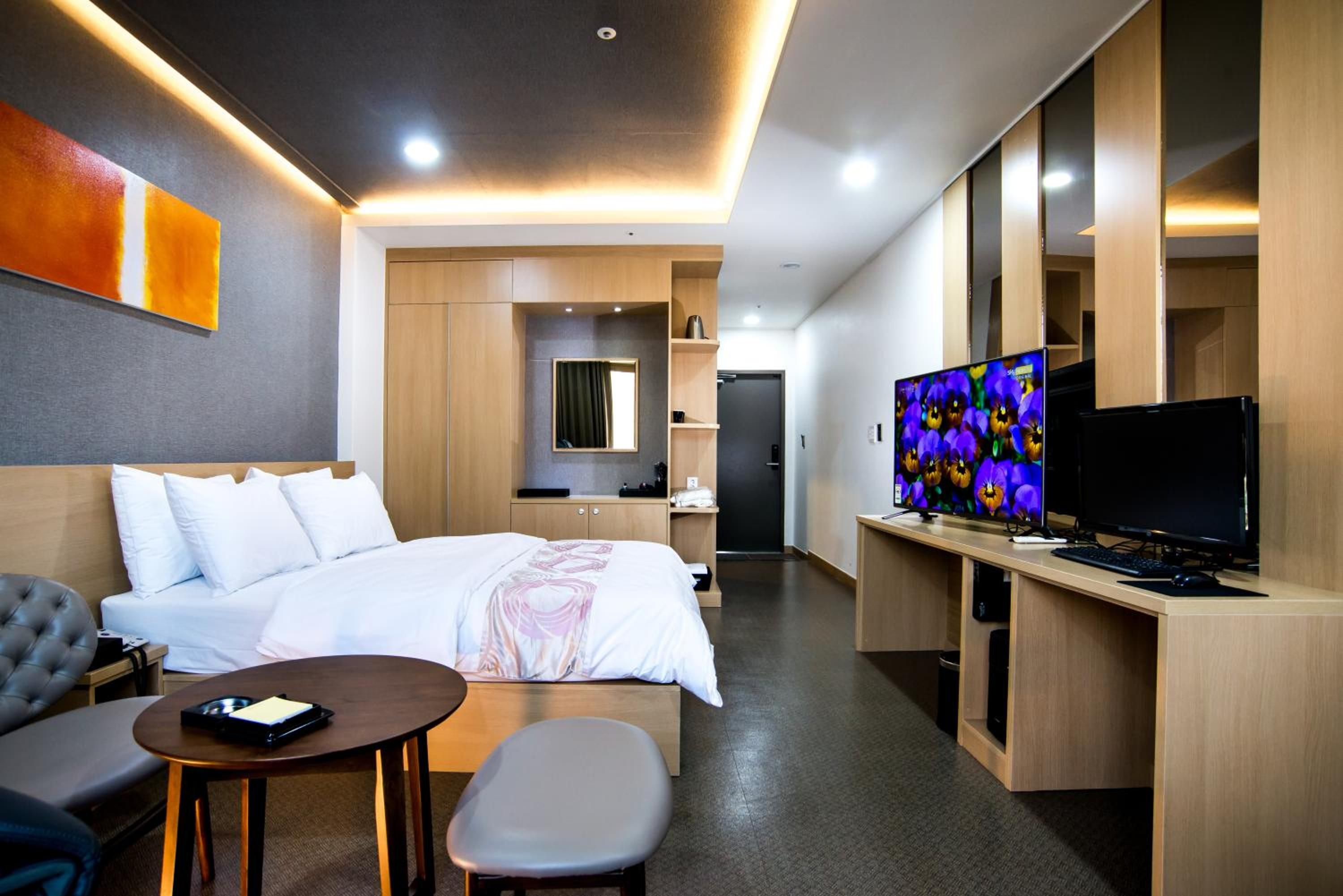 Ein Hotelzimmer mit Bett, Schreibtisch mit Computer, Fernseher und einer Sitzecke.