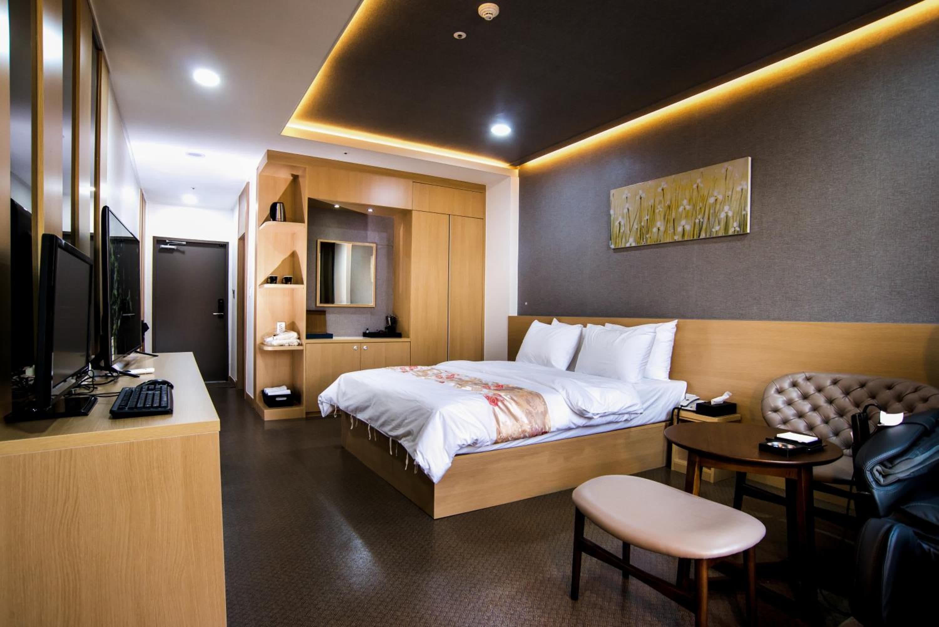 Una habitación de hotel moderna con cama, escritorio, silla y obras de arte.