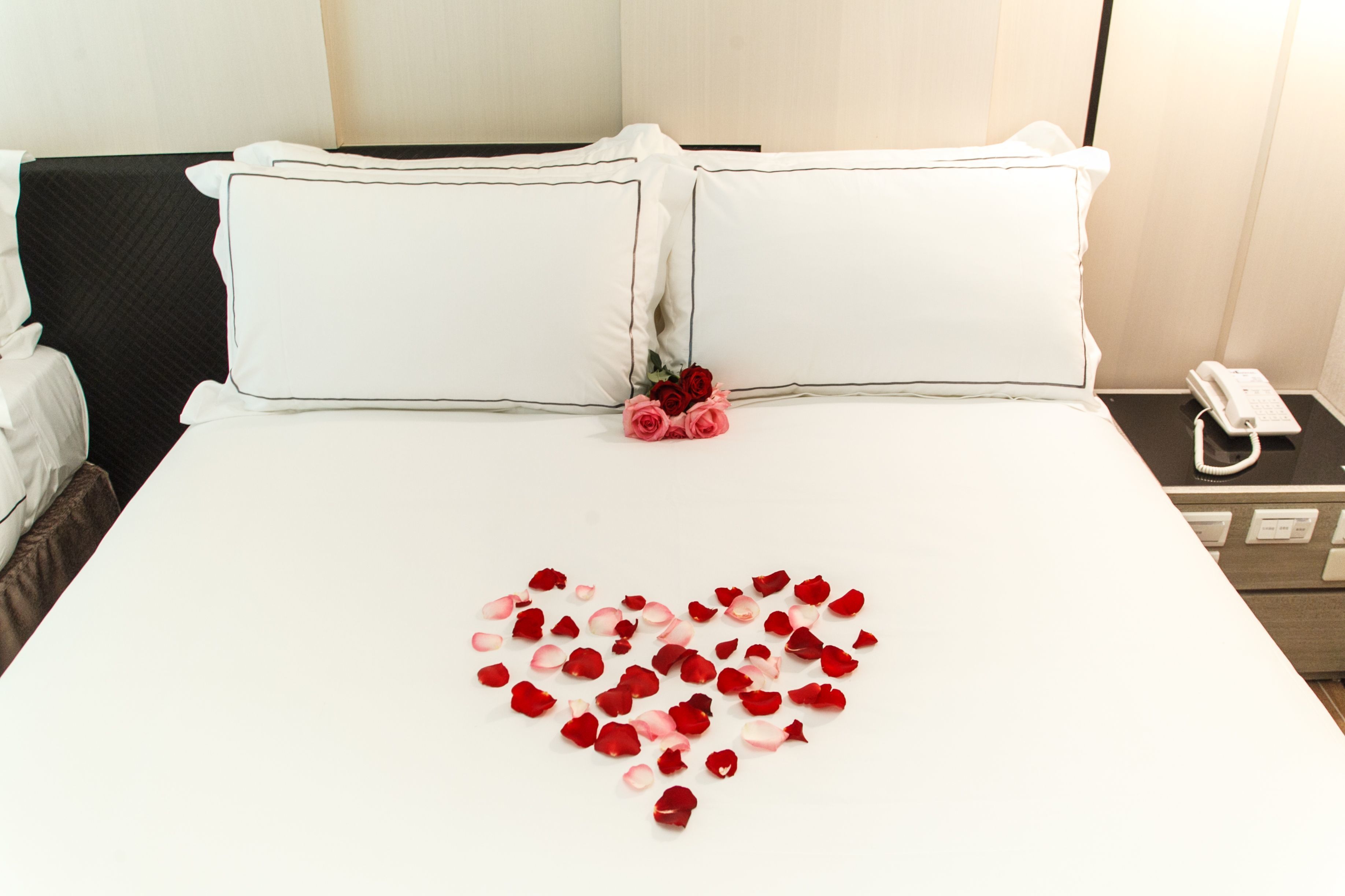 Una habitación de hotel con una cama bien hecha, un teléfono en la mesita de noche y una lámpara de pared.