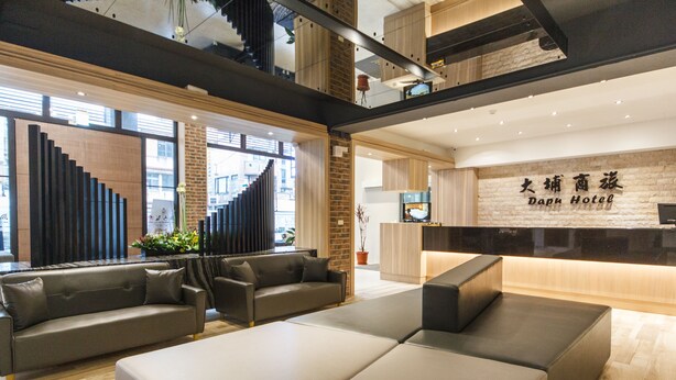 Un moderno vestíbulo de hotel con una recepción, zona de estar y una escalera.