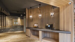 Un mostrador de recepción con detalles de madera, dos lámparas colgantes y un monitor de ordenador.