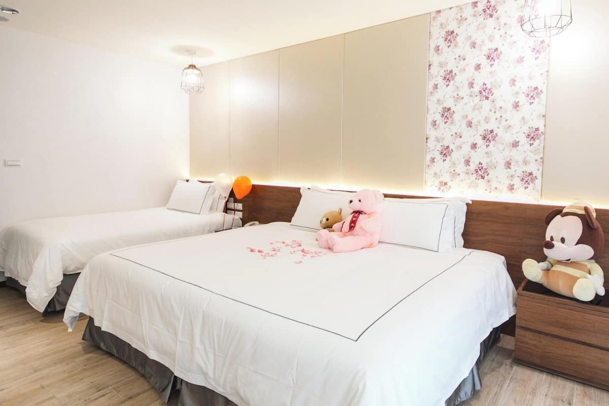 A hotel room with two beds, a nightstand, a mirror, and a floral wallpaper.