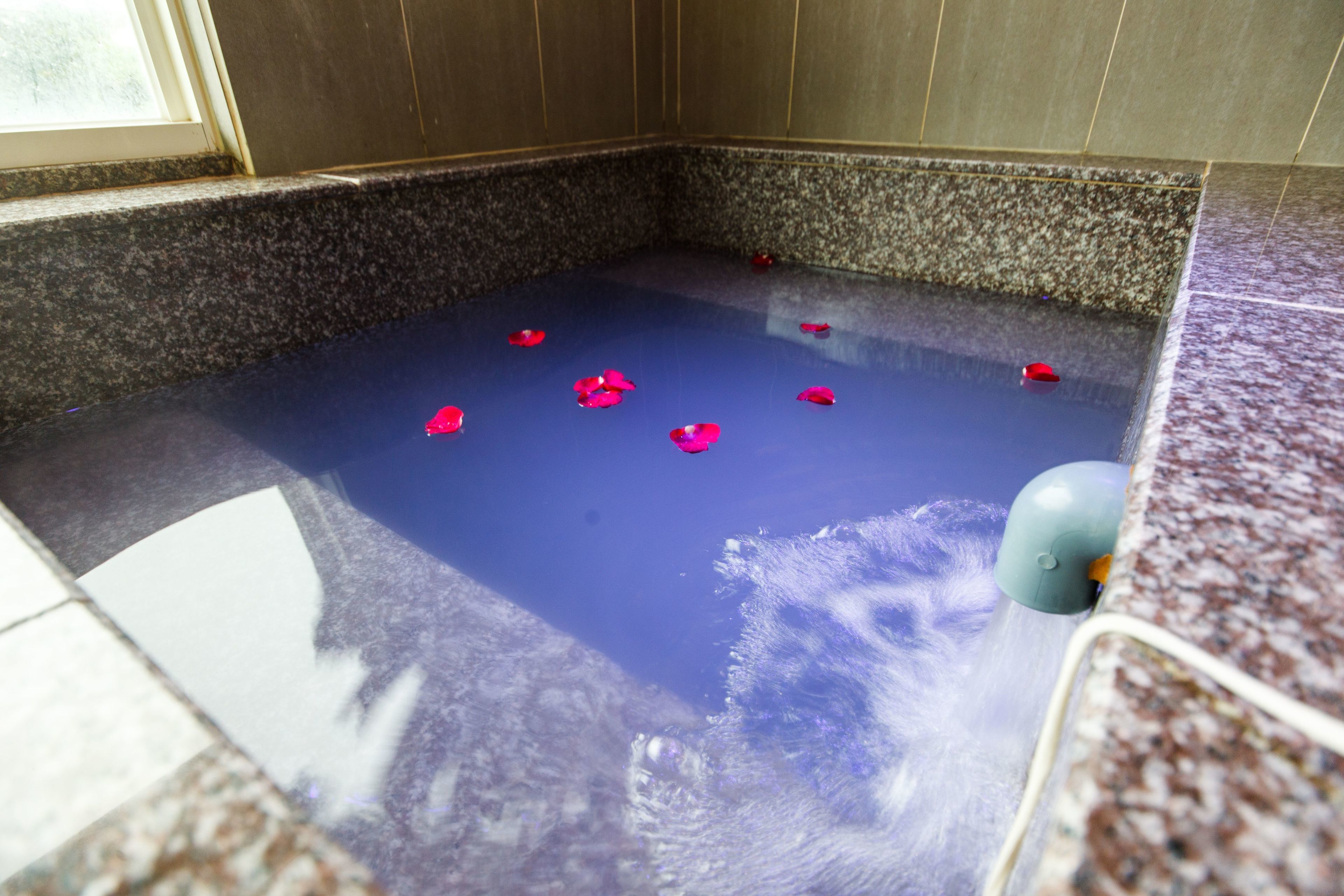 Un baño spa con interior azul, paredes de granito y suelo de mármol.