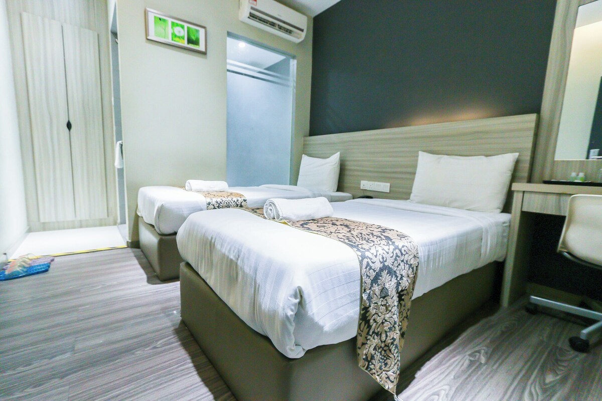 A hotel room with two beds, a desk, and a chair.